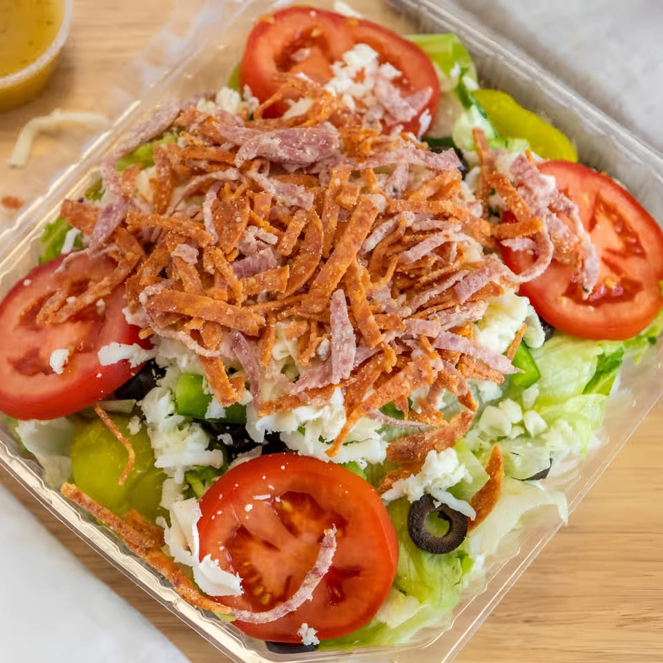 Antonious N&W Pizza's salad with lettuce, tomatoes, olives, cheese, and pepperoni in a plastic container.