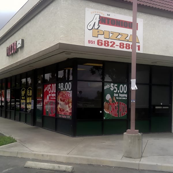 Exterior view of Antonious N&W Pizza restaurant with large windows displaying pizza deals.