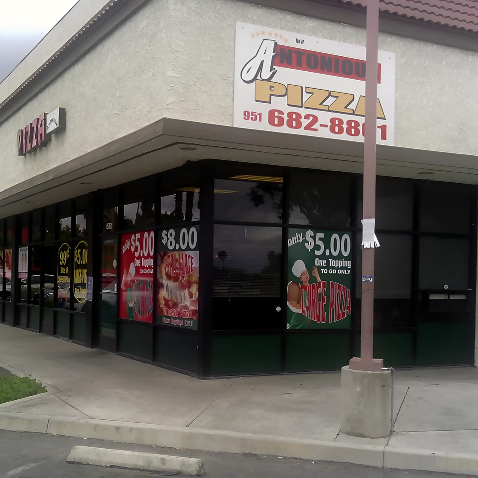 Exterior view of Antonious N&W Pizza restaurant with large windows displaying pizza deals.