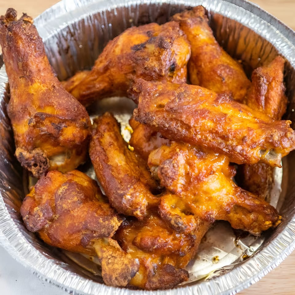 Antonious N&W Pizza's crispy, golden-brown chicken wings in a foil container.